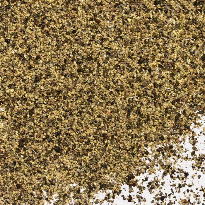 Pepper Black Fine #1 by Whole Spice Inc., often called the king of spices, is sprinkled over a white surface, with the fine black pepper concentrated in the upper left corner and gently spreading out towards the lower right.