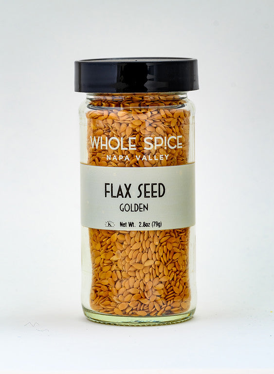 A glass jar with a black lid, labeled "Whole Spice Inc. Flax Seeds Golden," contains 2.8 oz (79 g) of golden flax seeds and is shown against a plain white background.