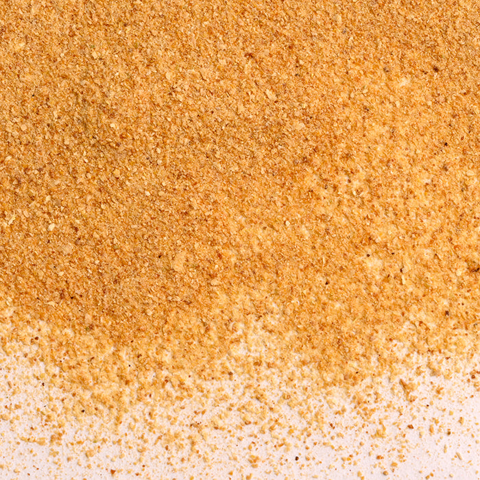 Close-up of light brown breadcrumbs scattered on a white surface—ideal for adding texture to baking or pairing with Whole Spice Inc. Lemon Peel Powder for a burst of citrus flavor.