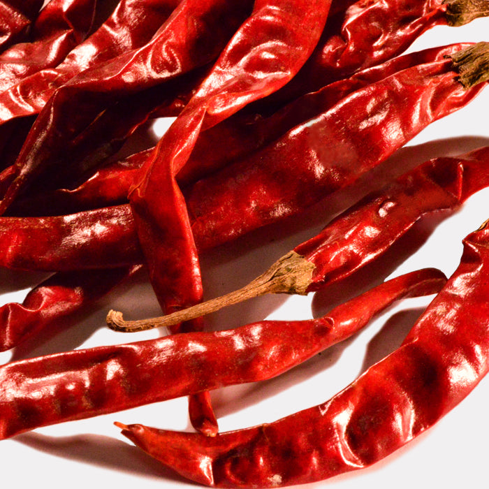 Whole Spice Inc. Chili De Arbol Whole peppers, with wrinkled, glossy skins, are scattered on a white surface—ideal for adding bold heat to spicy salsa or Mexican chili.