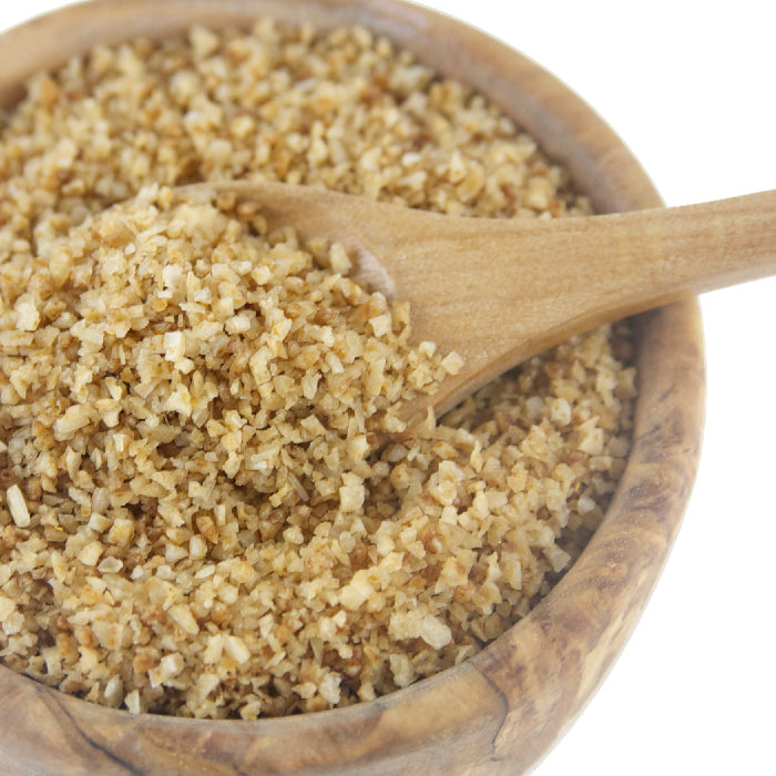 A wooden bowl filled with coarse, light brown bulgur wheat sprinkled with Whole Spice Inc. Habanero Salt, and a wooden spoon resting inside the bowl. The background is white.