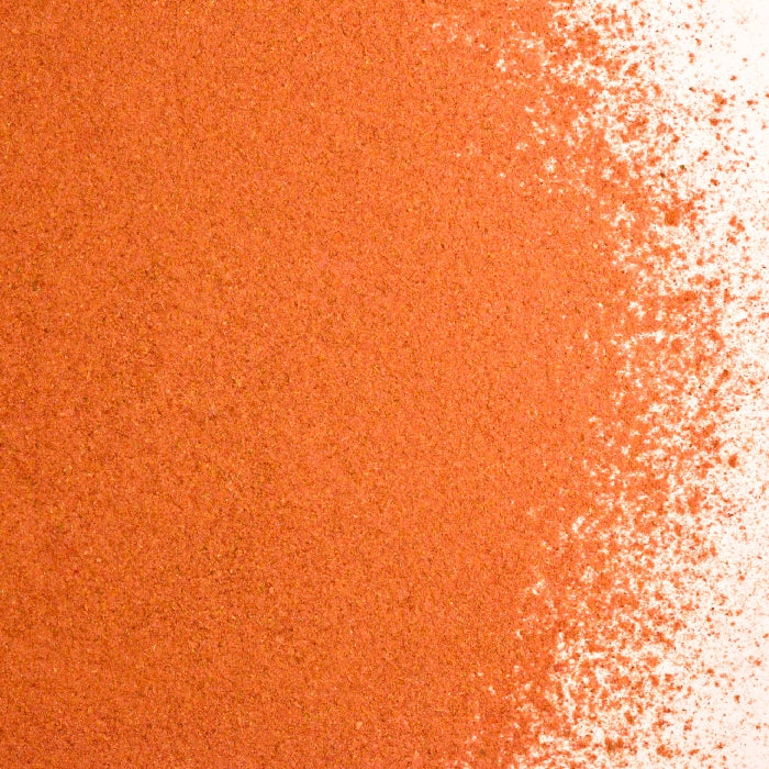 A close-up of fine orange-red powder, transitioning from dense to light coverage, evokes the warm hues of Whole Spice Inc.’s Hot Rosa Tea - Caffeine Free.