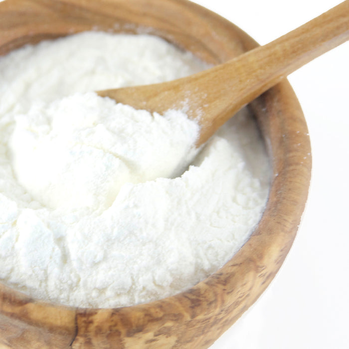 A wooden bowl filled with Whole Spice Inc. Lime Juice Powder, with a wooden spoon resting inside—ideal for baking or mixing as a lime juice substitute.