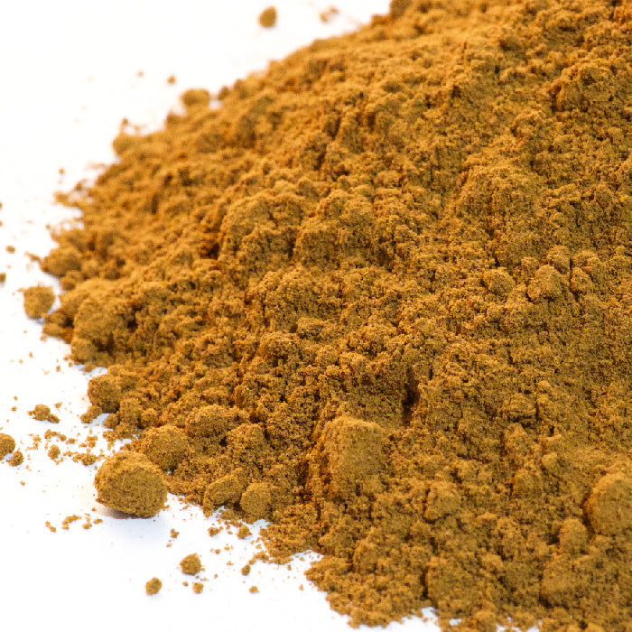 A close-up of Cinnamon Powder Saigon by Whole Spice Inc., showing a pile of rich brown cinnamon spread on a white surface.