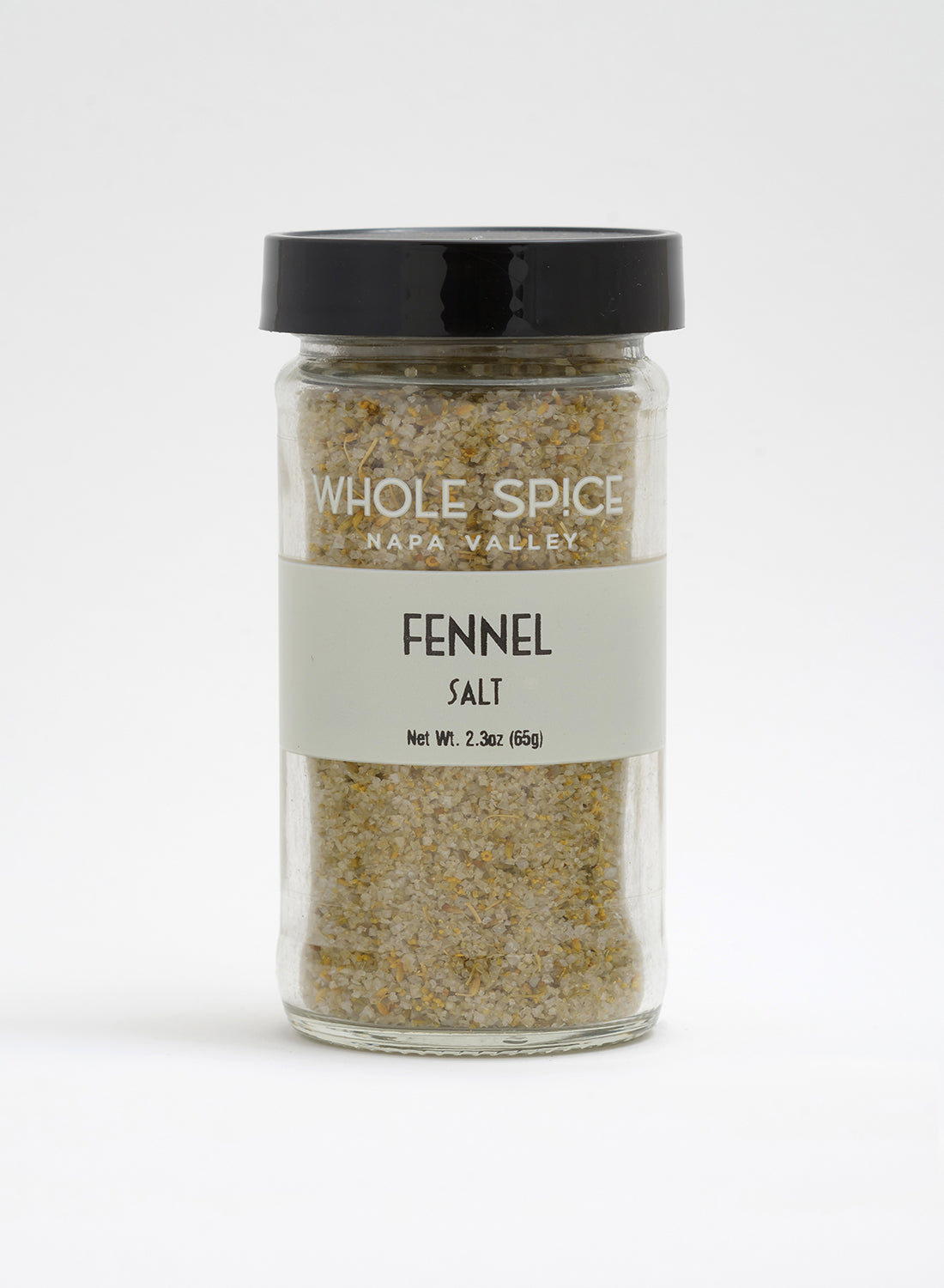 A clear glass jar with a black lid, labeled Whole Spice Inc. Fennel Salt, Net Wt. 2.3oz (65g), containing a coarse fennel sea salt blend in light yellow and white tones.