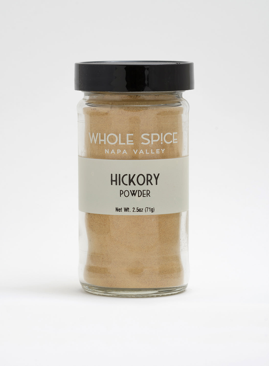 A glass jar of Hickory Powder by Whole Spice Inc. with a black lid and beige label (net wt. 2.5 oz/71 g) is shown against a white background, highlighting its bold smoked hickory flavor.