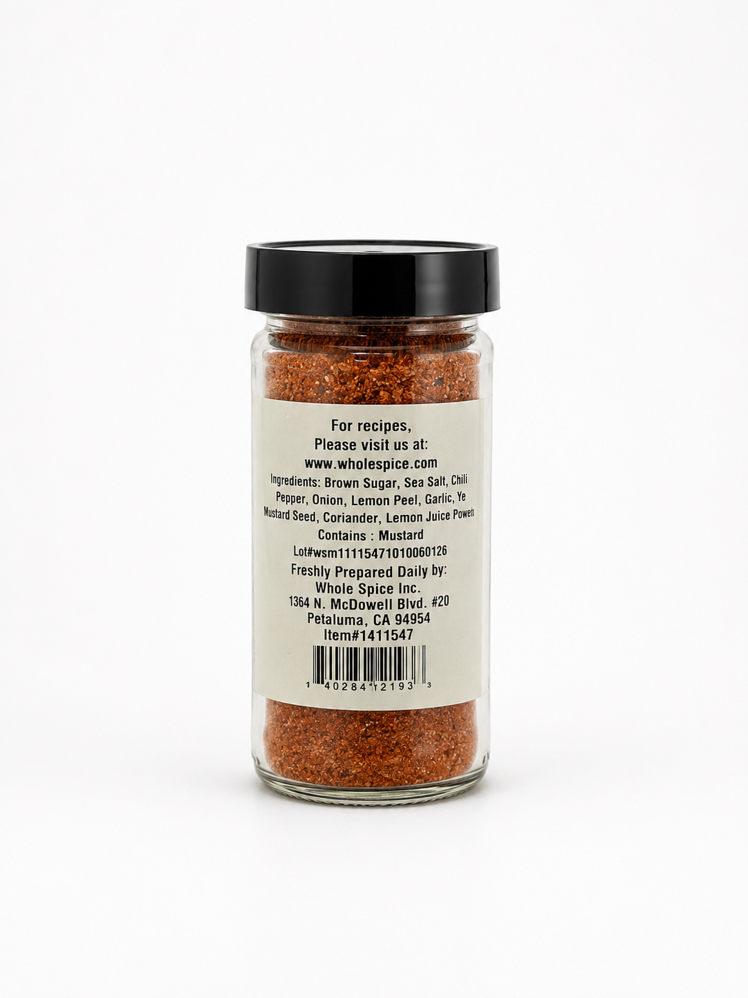 A glass jar with a black lid contains Northwest Salmon Rub, a red-brown spice blend by Whole Spice Inc., perfect for gourmet fish seasoning or as a salmon rub. The label provides ingredients and contact information for Whole Spice Inc., including an address and website with cedar plank salmon recipes.