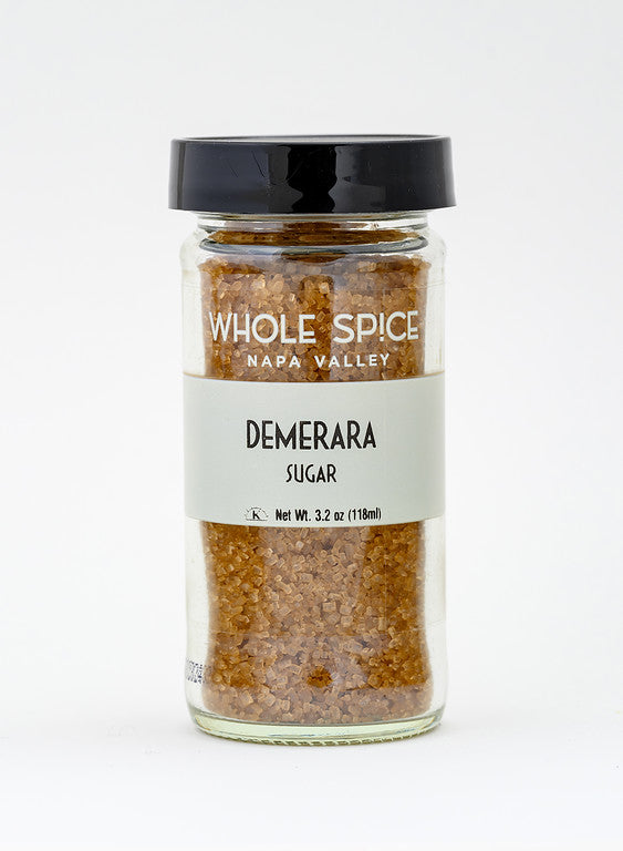 A clear glass jar of Whole Spice Inc. Demerara Sugar, filled with coarse brown cane sugar featuring a rich molasses flavor, and capped with a black screw-on lid. Net weight: 3.2 oz (118 ml). Photographed on a white background.