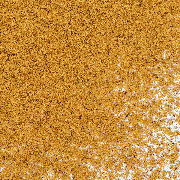 A close-up of a scattered pile of brownish-yellow granules on a white surface, resembling Whole Spice Inc.'s Hawaj Coffee Spice blend.