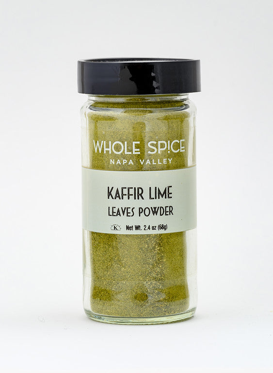 A clear glass jar with a black lid holds Kaffir Lime Powder by Whole Spice Inc., Net Wt. 2.4 oz (68g). Ideal for enhancing Asian dishes with authentic citrus flavor. Plain white background.
