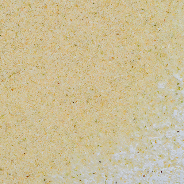 Close-up of Onion Granulated by Whole Spice Inc.: a light yellow, granular powder with tiny green and brown specks, highlighting the textured surface of this versatile dehydrated onion ingredient.