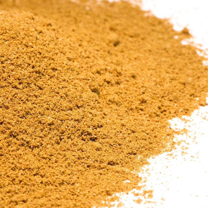 A close-up of Whole Spice Inc.'s Celery Stalk Powder, a light brown ground spice made from dehydrated celery, spread on a white surface.