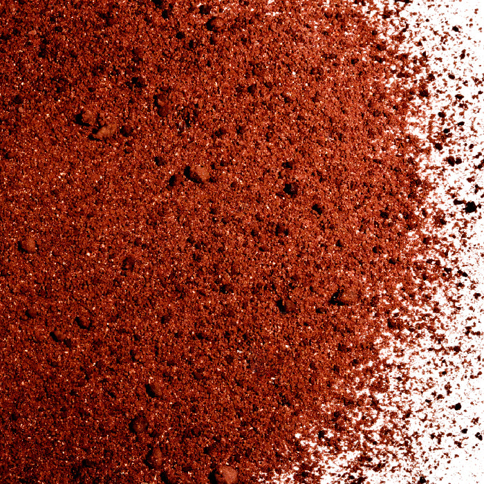 A close-up of loose, reddish-brown Cinnamon Chocolate Latte Spice by Whole Spice Inc. is spread on a white surface. The fine texture with small clumps suggests it's ideal for adding warmth to lattes or hot cocoa.