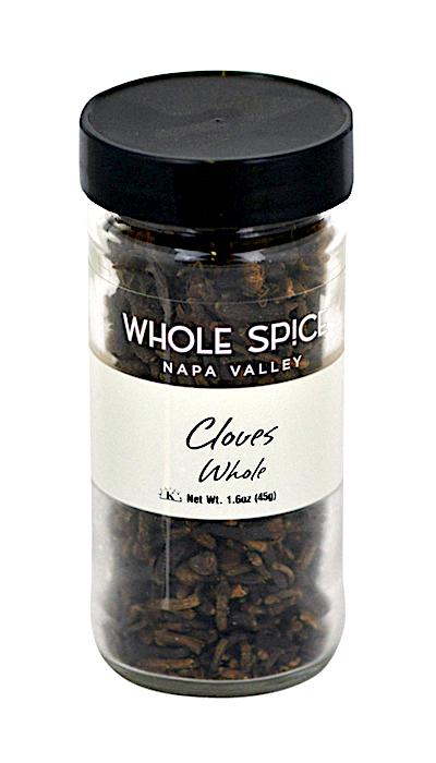 A clear glass jar from Whole Spice Inc. labeled “Cloves Whole” contains aromatic dried Syzygium aromaticum buds (whole cloves) with a black screw-on lid, white label, and net weight of 1.6 oz (45g).