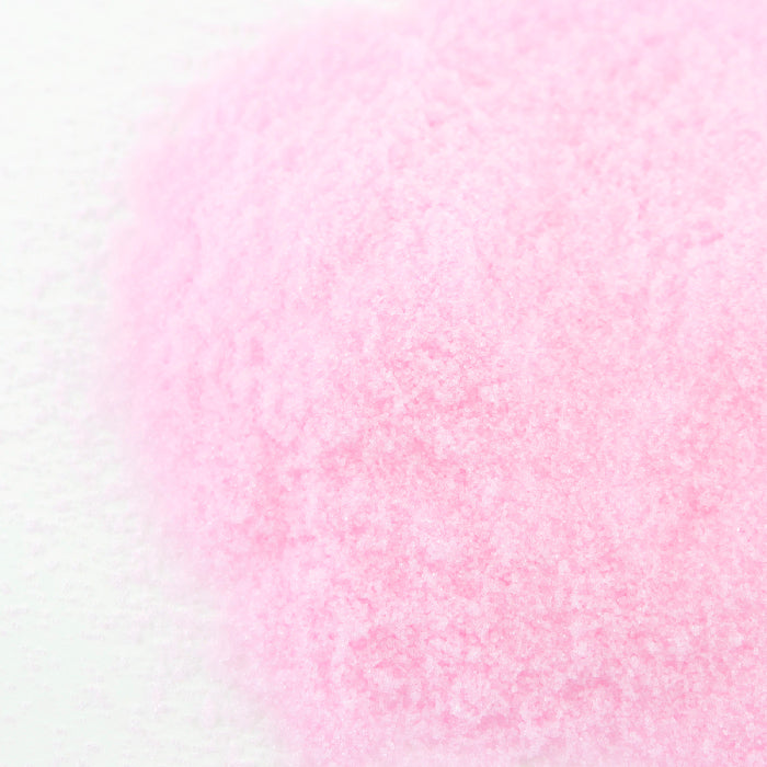 A close-up of Whole Spice Inc. Curing Salt, a fine, pale pink salt spread on a white surface, commonly used for pickling and preserving meats.