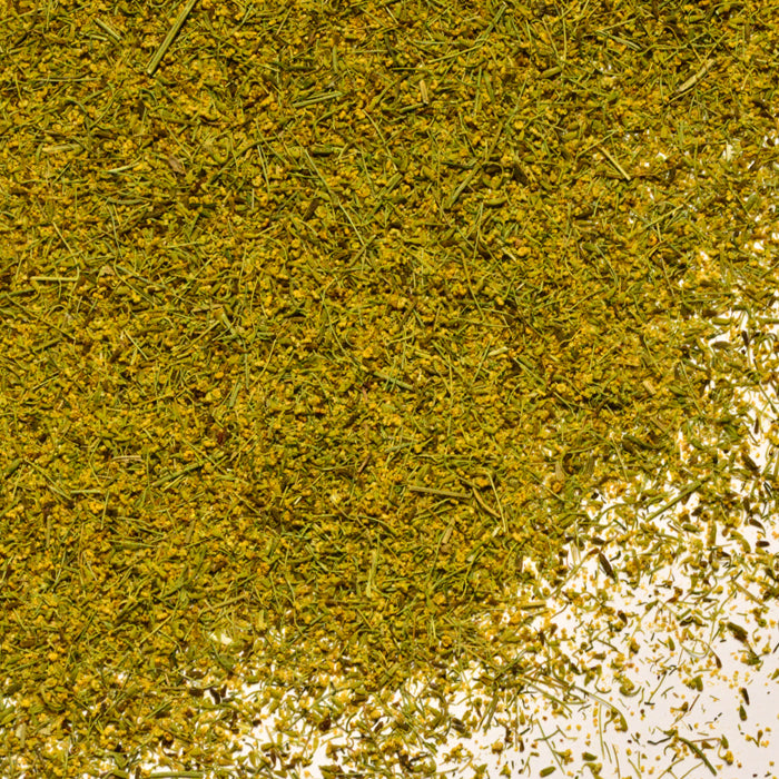 A close-up of Whole Spice Inc. Dill Pollen scattered on a white background, showing its unique texture—ideal for seasoning fish dishes.