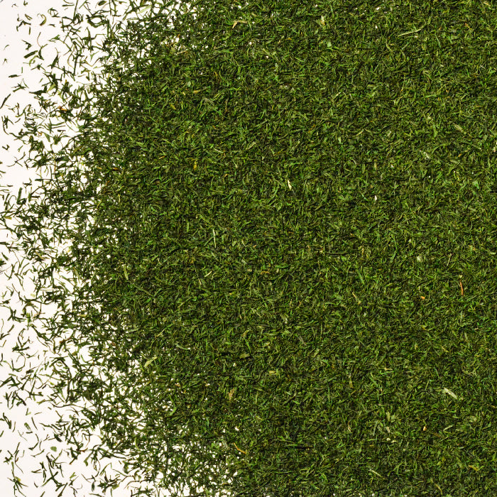 Whole Spice Inc. Dill Weed is scattered in a circular pile on a white background, with some loose leaves extending beyond the main cluster.