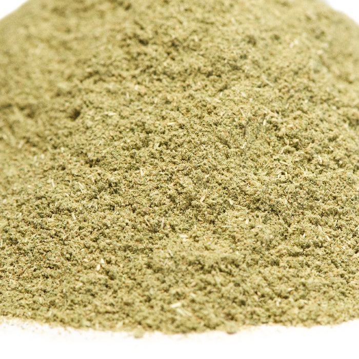 A close-up of Epazote Powder by Whole Spice Inc., a finely ground greenish-brown blend from dried epazote leaves, commonly used in herbal tea infusions, shown on a white surface.