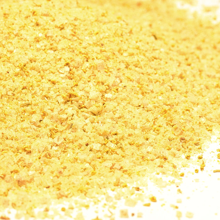 A close-up view of Whole Spice Inc. Fennel Salt, a flavorful seasoning blend, scattered on a white surface.