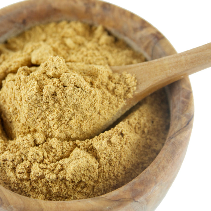 A wooden bowl of Whole Spice Inc. Hickory Powder with a wooden spoon scooping the spice, featuring a subtle smoked hickory flavor.