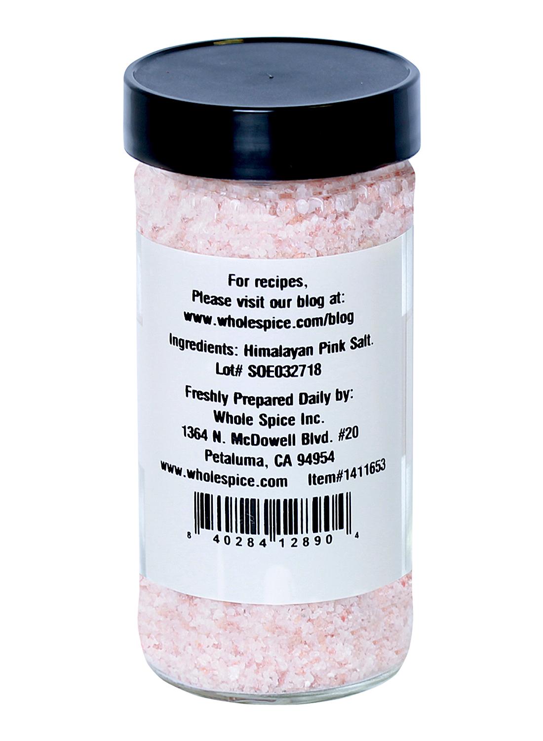 A clear jar with a black lid contains Whole Spice Inc. Himalayan Pink Salt Fine #1 (0.2-0.8mm). The back label lists ingredients, trace minerals, company details, location info, barcode, and a blog link with recipes.