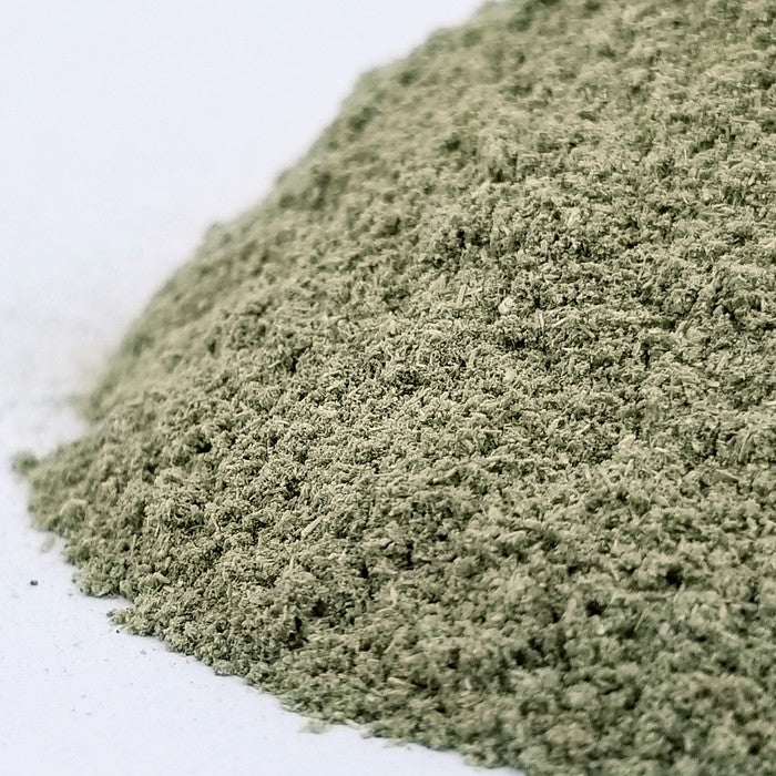 A close-up of Hyssop Herb Powder by Whole Spice Inc.—a fine, greenish-grey powder from the aromatic hyssop shrub—displayed on a white surface.