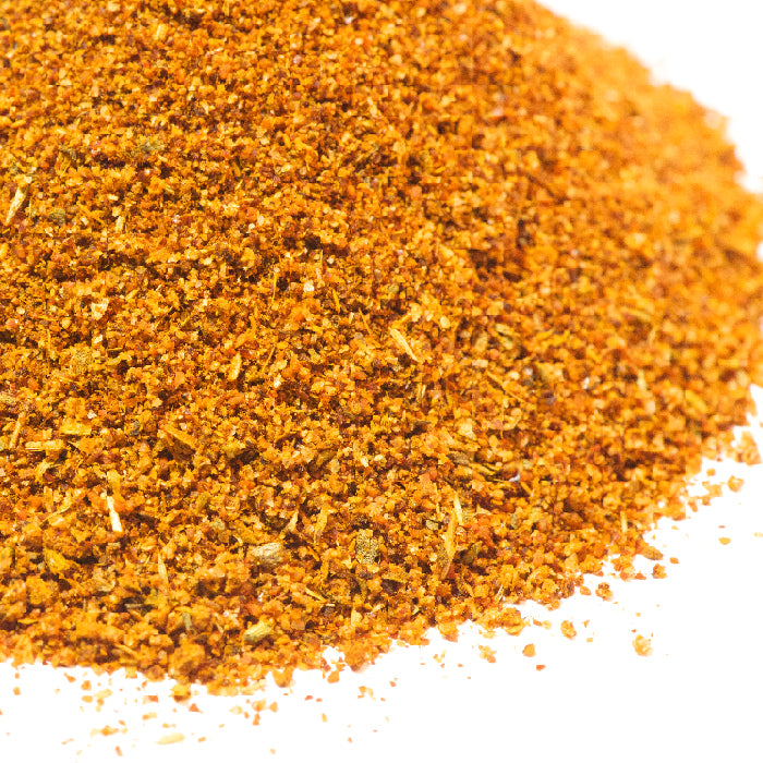 A close-up of Istanbul Grill Seasoning by Whole Spice Inc., a finely ground orange and brown blend on a white background, commonly used in Mediterranean cuisine to season dishes such as Turkish kebabs.