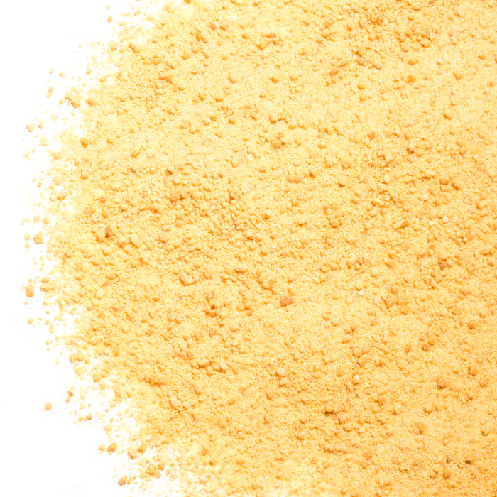 A close-up of Whole Spice Inc. Maple Salt—a fine, yellow-orange gourmet seasoning with pure maple syrup—spread unevenly on a white surface.