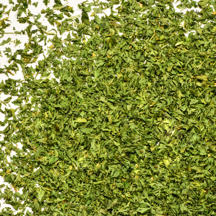 A close-up of Whole Spice Inc. Parsley Flakes shows their fine, leafy texture—these dried herbs are perfect for garnishing dishes and adding fresh flavor.