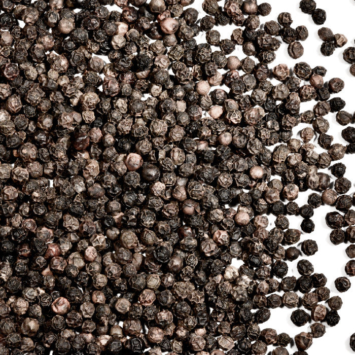 A close-up of Whole Spice Inc. Peppercorns Black Smoked—known as the King of Spices—scattered on a white background.