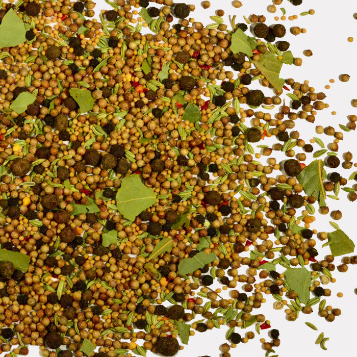 A close-up of Whole Spice Inc. Pickling Spice, featuring whole black peppercorns, coriander and fennel seeds, bay leaves, and dried herbs—perfect for chutneys or pickled vegetables—scattered against a white background.