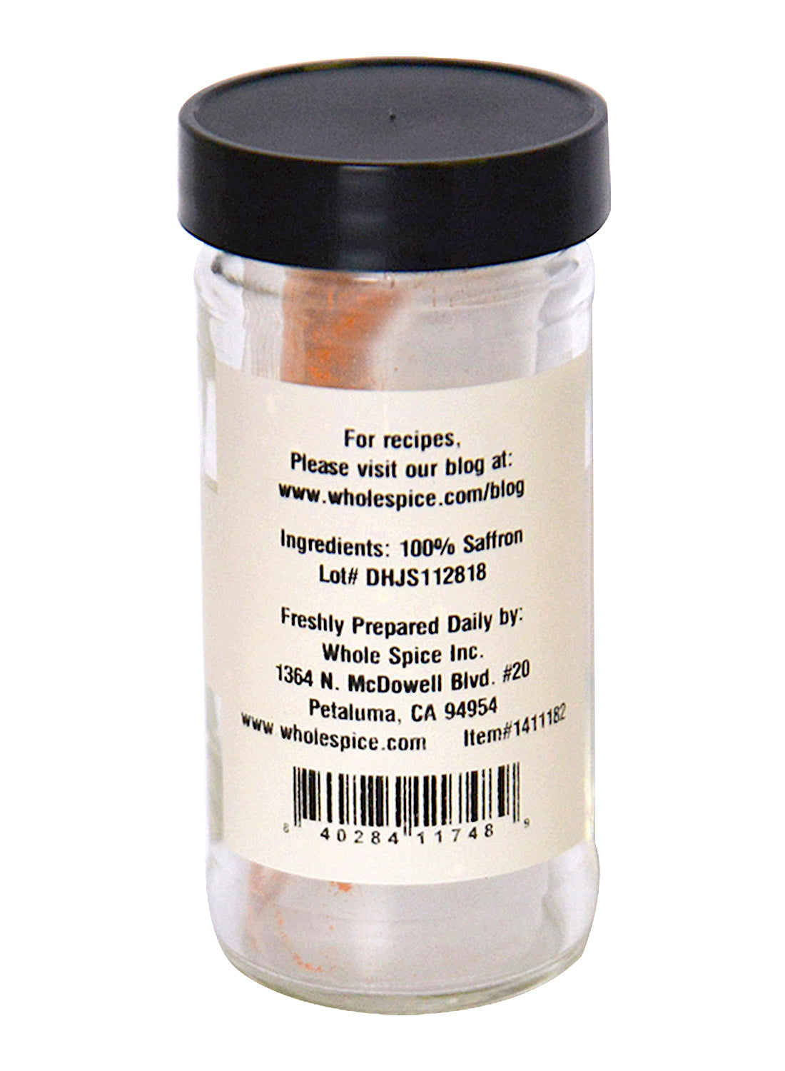 A clear glass jar with a black lid holds Whole Spice Inc. Saffron Powder. The white label lists 100% saffron, the producer’s address, lot number, and a website for recipes.