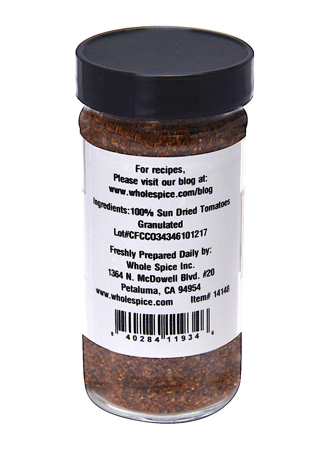 A clear jar with a black lid from Whole Spice Inc., labeled "Sun Dried Tomatoes Granulated, 100% sun-dried." The reddish-brown, granular spice adds bold flavor to pasta or salads. Label includes company info and barcode.