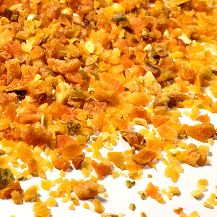 A close-up of Whole Spice Inc. Sweet Potato Dices—small, dried orange and yellow fruit pieces—scattered on a white surface.