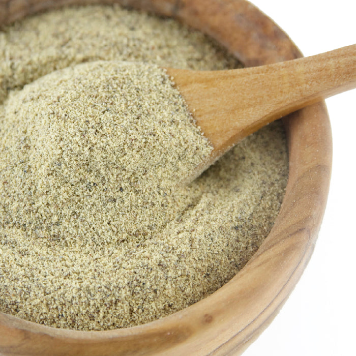 A wooden bowl with Whole Spice Inc. Pepper White Powder, featuring a wooden spoon heaped with the fine seasoning—ideal for enhancing white sauces.